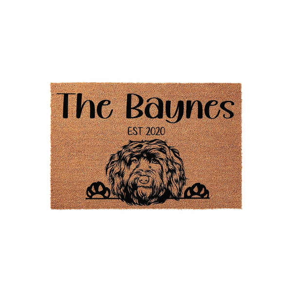 Personalized Goldendoodle Doormat featuring a cute illustrated dog peeking over the bottom edge, printed on a natural tan coir fiber mat with custom family name text and established year in bold black lettering for a front porch.