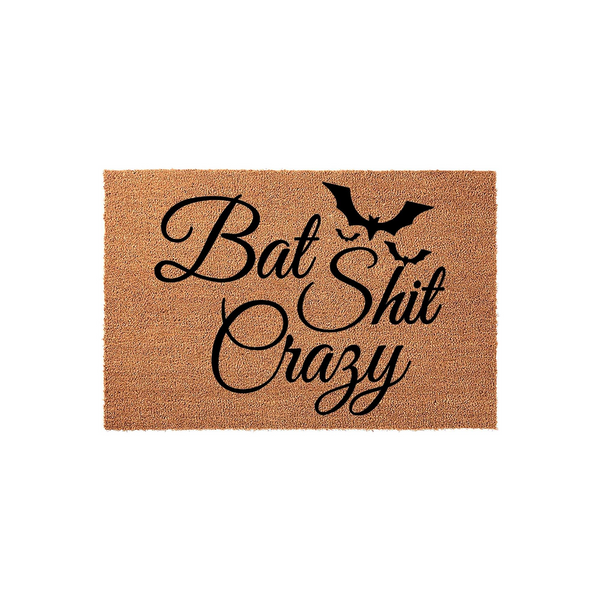 Funny Bat Shit Crazy coir doormat featuring a black silhouette of a flying bat above bold, cursive typography on a natural brown textured fiber background, perfect for a humorous Halloween or gothic home entryway decor statement.