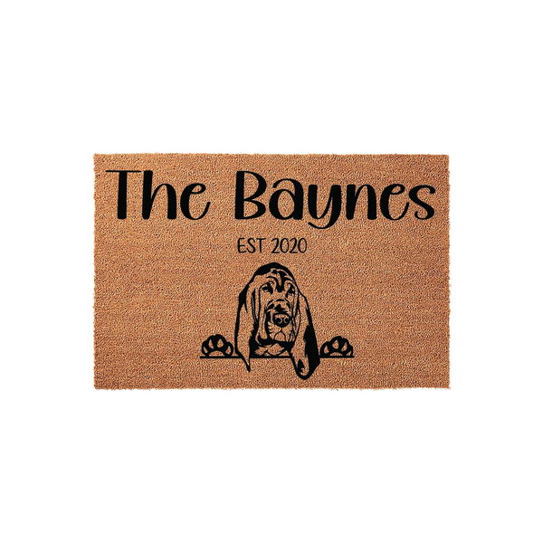 Personalized Basset Hound doormat featuring a natural coir texture with a black printed illustration of a Basset Hound peeking over the bottom edge, customized with a family name and established year on a clean white background.