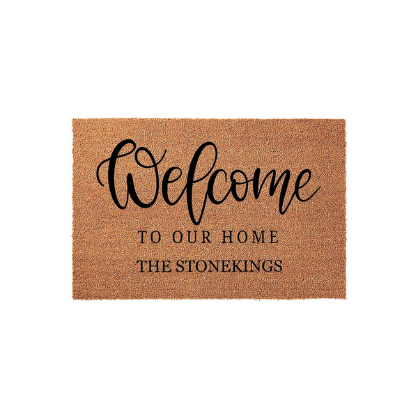 Personalized Welcome To Our Home Doormat featuring a natural coir fiber texture with elegant black script and serif lettering, creating a custom entryway rug that displays a family name for a warm and inviting front porch