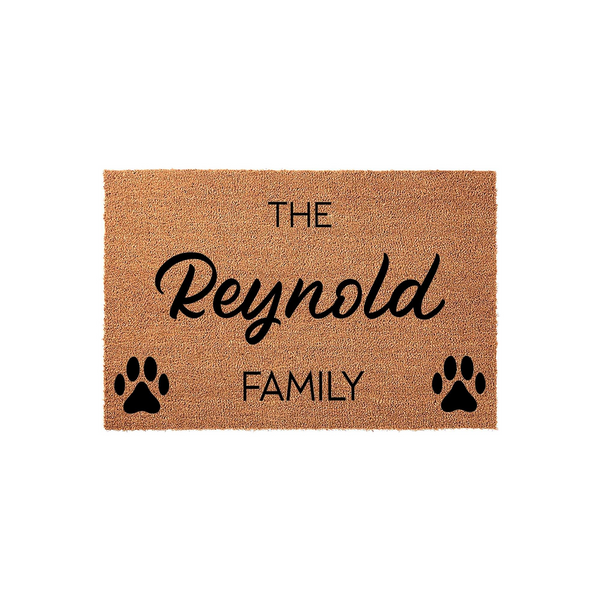 Personalized family name coir doormat featuring a natural brown fiber texture, printed with the text The Family and black paw prints on either side, creating a welcoming entryway decor piece for pet lovers and their homes.