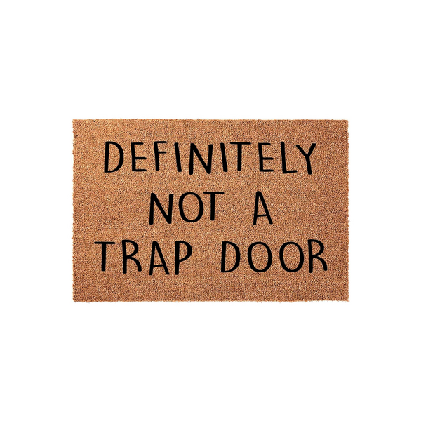 Funny Doormat with the text Definitely Not A Trap Door printed in bold black letters on a natural tan coir fiber background, creating a humorous and welcoming entrance piece for any home front porch or entryway decor.