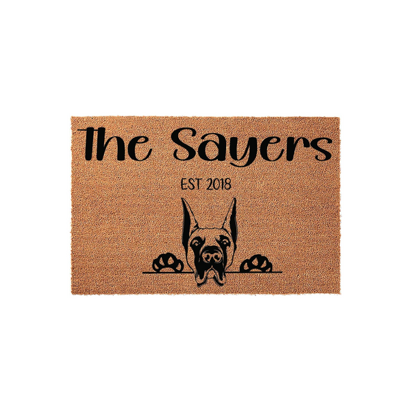 Personalized Doberman Pinscher doormat featuring a natural coir texture with a black graphic of a dog peeking over a line, customized with a family name and established year for a welcoming front porch entrance decor piece.