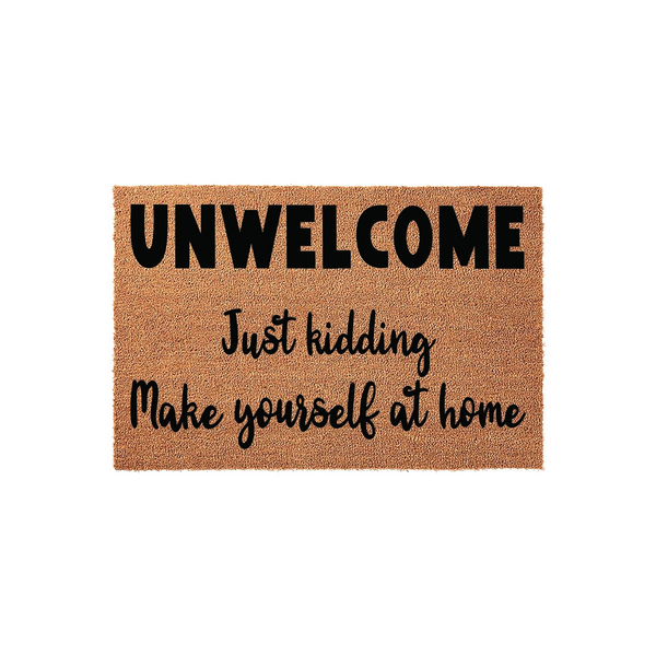 Funny coir doormat featuring the text Unwelcome Just kidding Make yourself at home in bold black lettering, displayed against a clean white background to showcase the natural fiber texture of this humorous front porch entry rug.