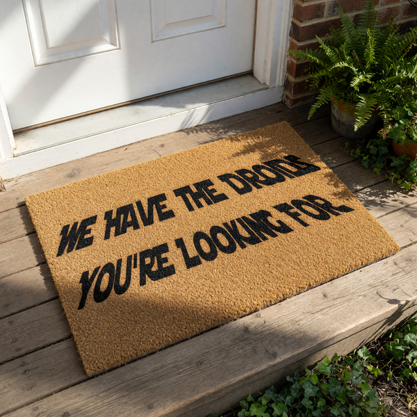 Funny sci-fi welcome doormat featuring bold black text that reads We Have The Droids You Are Looking For on a natural brown coir fiber mat, perfect for a geeky home entrance, front porch decor, or a unique housewarming gift for