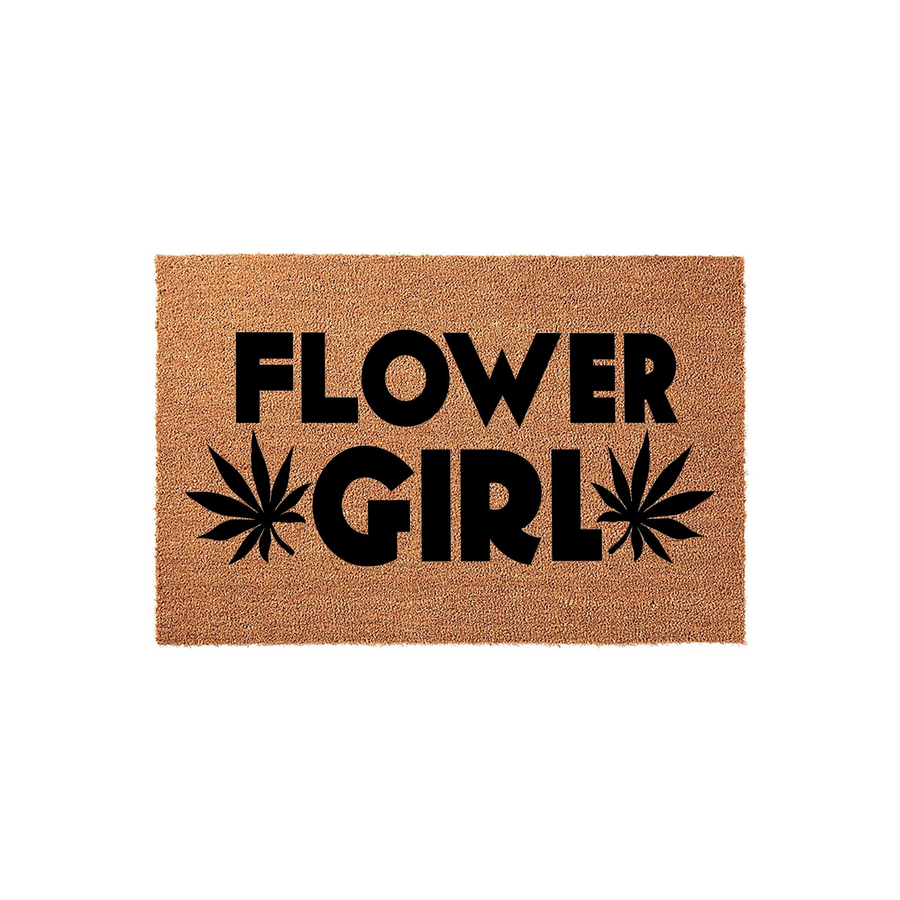 Flower Girl coir doormat featuring bold black text and stylized cannabis leaf graphics on a natural brown coconut fiber background, creating a fun and unique entryway decor piece for a home with a relaxed, bohemian aesthetic.