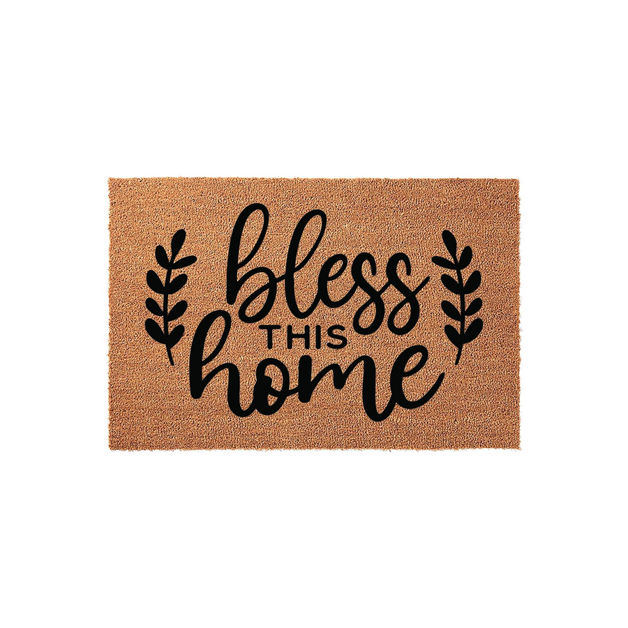 Bless This Home coir doormat featuring a natural tan fiber texture and bold black script lettering, accented by simple leaf sprigs on each side to create a welcoming farmhouse aesthetic for your front porch entryway decor.