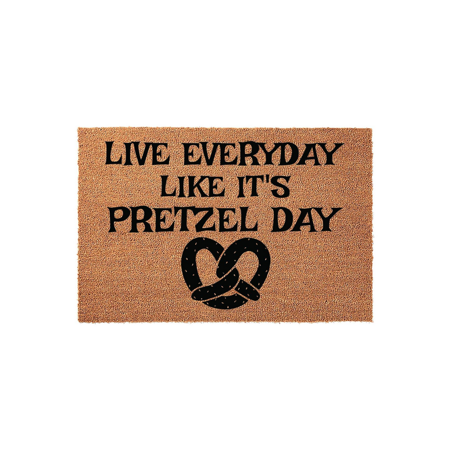 Live Everyday Like It's Pretzel Day coir doormat featuring bold black text and a large pretzel graphic centered on a natural brown fiber background, perfect for a fun and humorous entryway decor statement for any kitchen or front