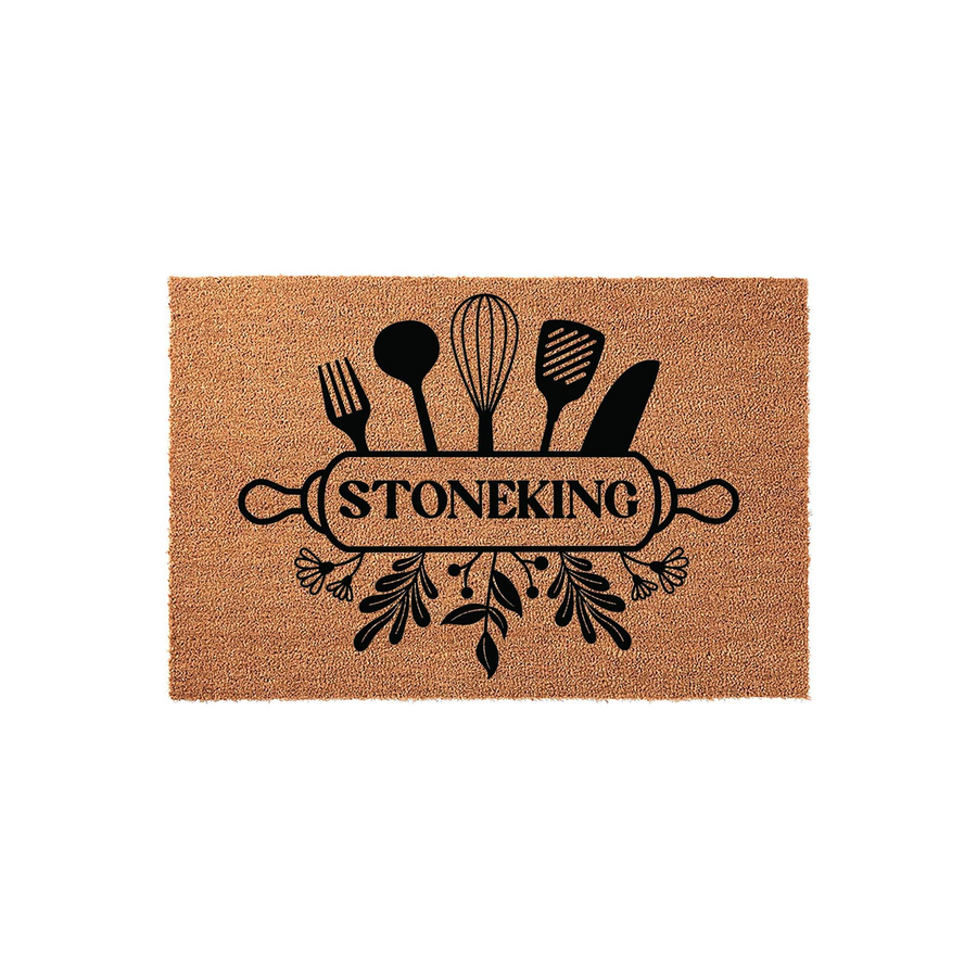 Personalized kitchen doormat featuring a black graphic of a rolling pin, whisk, and various cooking utensils over a natural coir background, with a custom family name printed in the center of the rolling pin design for a home