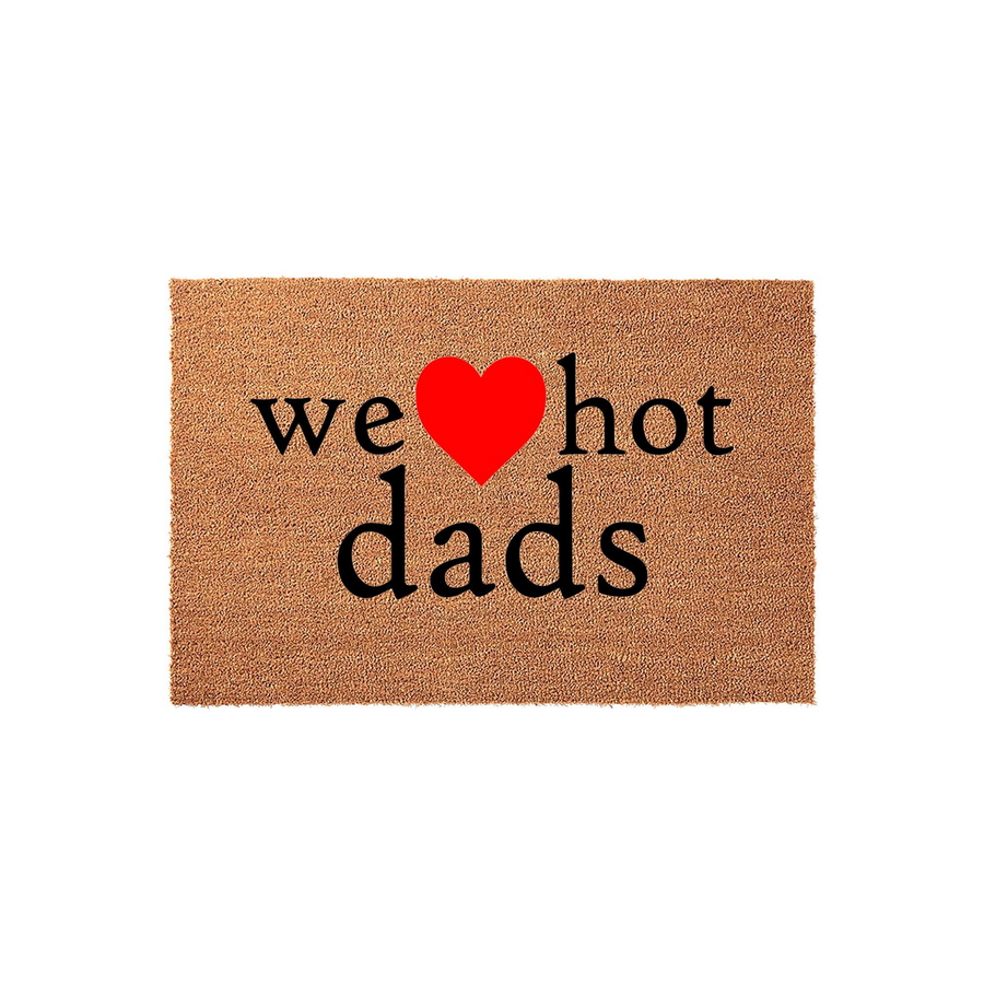 We Heart Hot Dads coir doormat featuring bold black text and a bright red heart icon centered on a natural tan fiber background, creating a humorous and welcoming entrance piece for any home entryway or front porch decor.