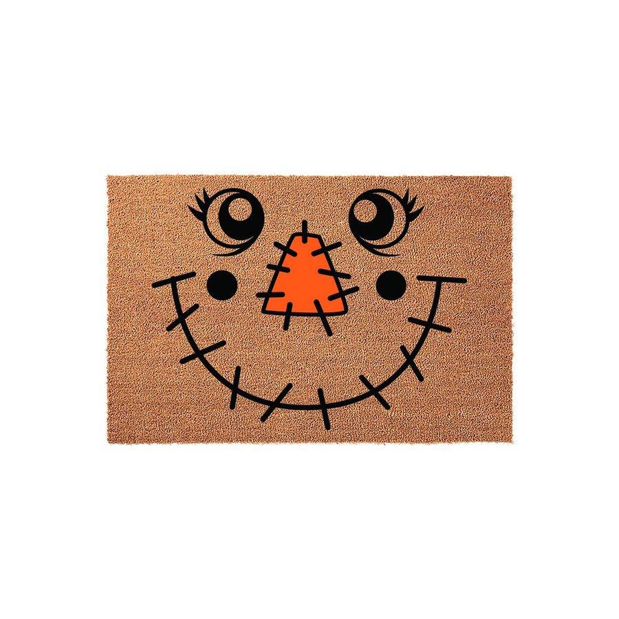 Scarecrow face coir doormat featuring a cheerful design with a bright orange stitched nose, large expressive eyes, and a wide stitched smile on a natural tan fiber background, perfect for adding festive fall decor to your front