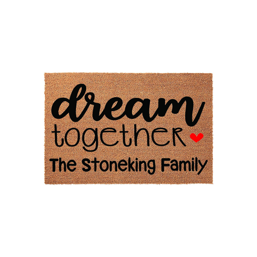 Personalized family name coir doormat featuring the phrase dream together in black script and block lettering with a small red heart accent, set against a natural tan textured coir background for a welcoming home entrance decor.
