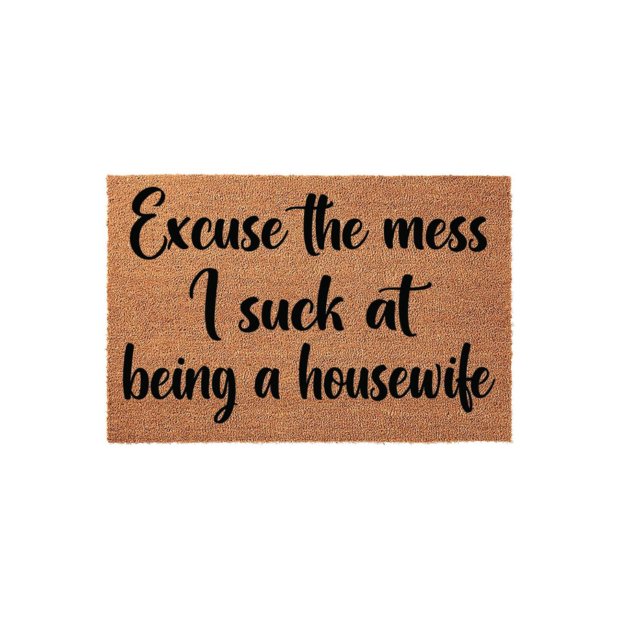 Funny Excuse the Mess I Suck at Being a Housewife doormat featuring bold black script lettering printed on a natural tan coir fiber mat, providing a humorous and welcoming touch to any front porch or entryway decor.