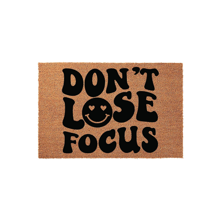 Don't Lose Focus coir doormat featuring bold black retro-style typography on a natural brown fiber background, with a smiling face icon replacing the letter O in the word lose to add a playful touch to your front porch entryway