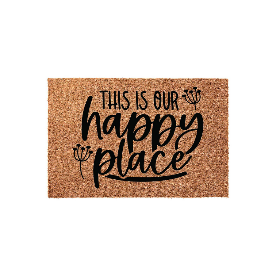 This Is Our Happy Place Coir Doormat features a natural tan fiber texture with bold black lettering and delicate floral accents, creating a welcoming entrance decor piece for any home entryway or front porch setting.