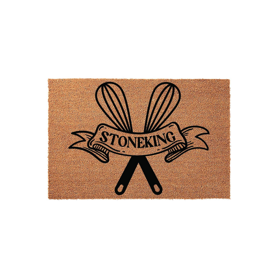 Personalized Kitchen Doormat featuring a black graphic of crossed whisks and a decorative banner with the family name Stoneking, set against a natural tan coir fiber background for a rustic and welcoming home entrance decor style.