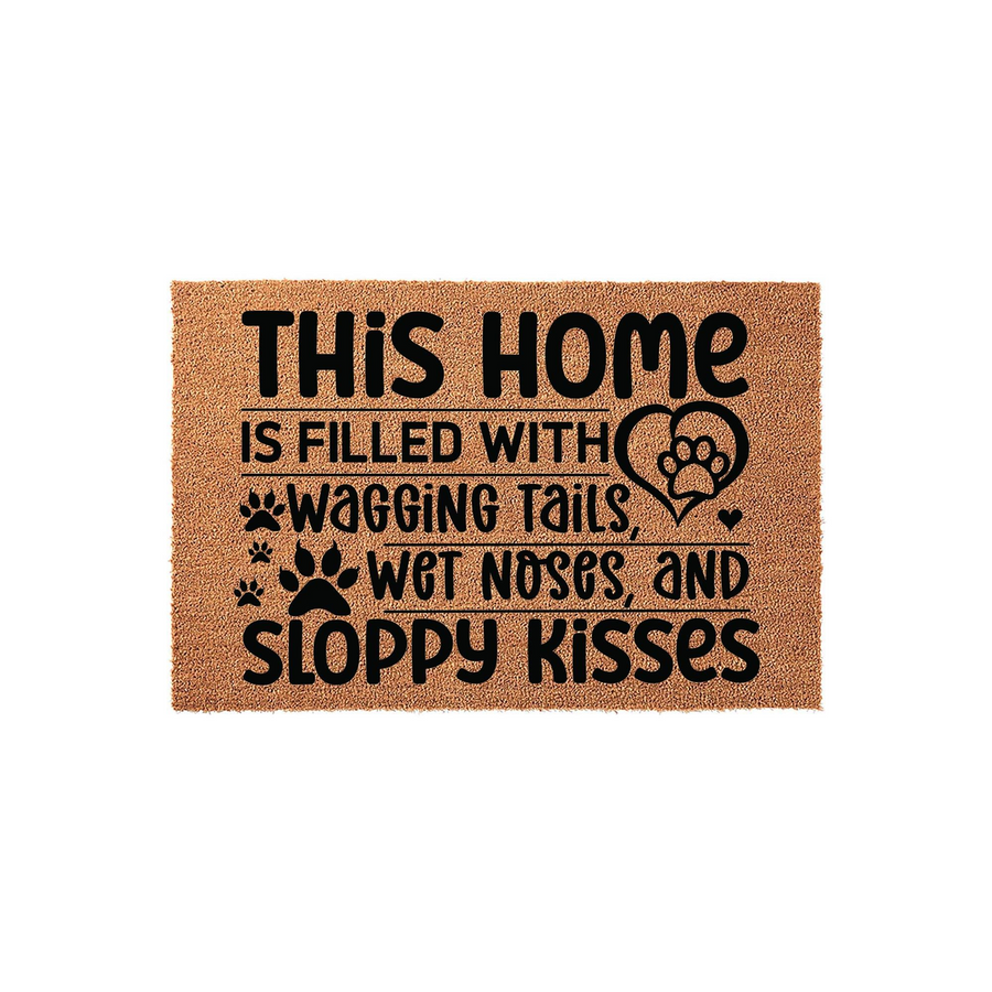 Dog lover coir doormat featuring the text This home is filled with wagging tails, wet noses, and sloppy kisses in black ink, set against a natural tan textured fiber background with cute paw print and heart graphic accents.