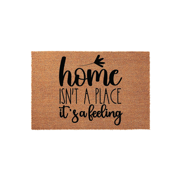 Home Isn't A Place It's A Feeling coir doormat featuring a natural brown fiber texture and bold black typography, centered on a plain white background to showcase the welcoming front porch decor style for your entryway or