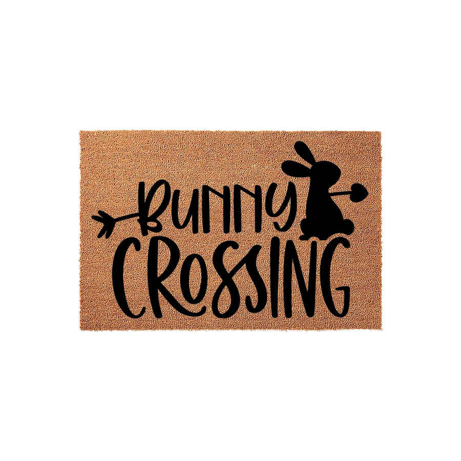 Bunny Crossing coir doormat featuring a playful black silhouette of a rabbit and decorative arrow text on a natural tan fiber background, creating a festive spring entryway decor piece for your front porch or home entrance.
