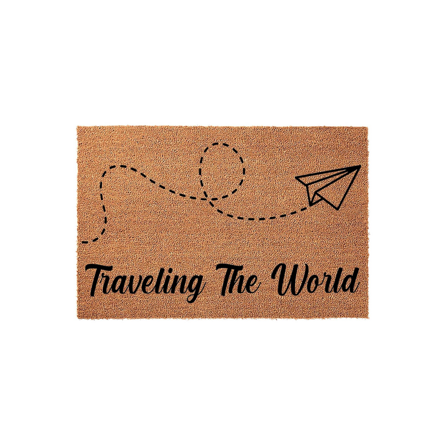 Traveling The World coir doormat featuring a black ink illustration of a paper airplane with a dashed flight path trail, set against a natural tan textured fiber background for a travel-themed home entrance decor piece.