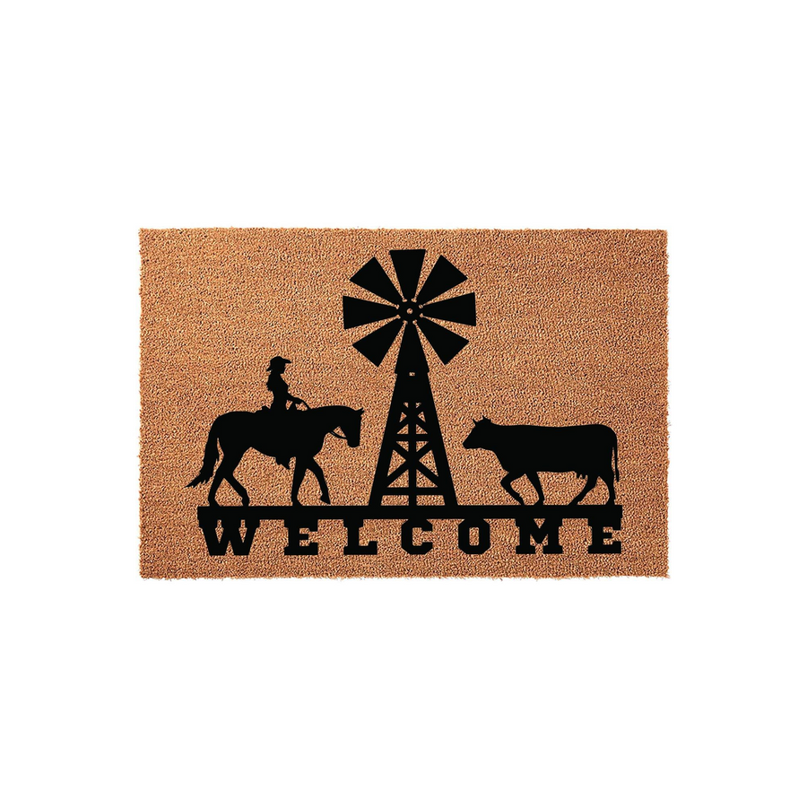 Farmhouse Welcome Doormat featuring a black silhouette of a cowgirl on horseback, a rustic windmill, and a cow standing on a natural coir fiber background with the word Welcome printed in bold black lettering at the bottom of the