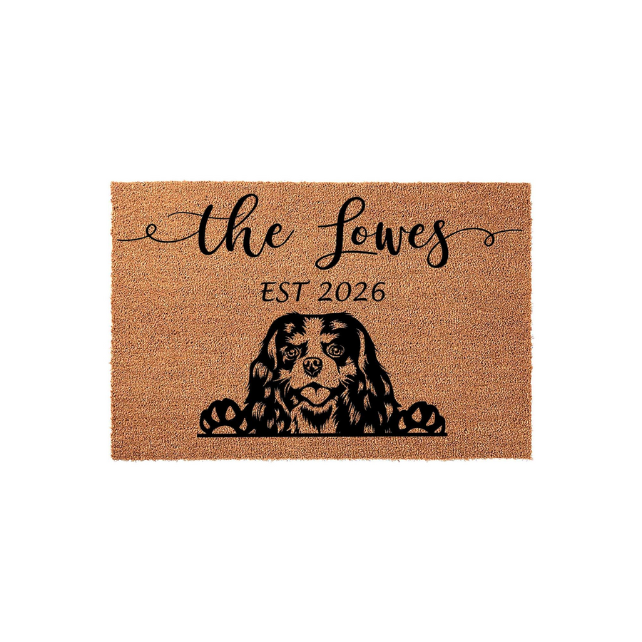 Personalized Cavalier King Charles Spaniel doormat featuring a cute dog peeking over the edge, customized with a family name and established year on a natural coir fiber background for a welcoming front porch entrance.