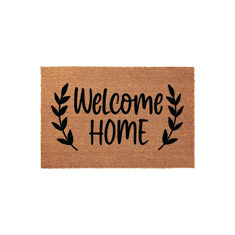 Welcome Home coir doormat featuring a natural tan fiber texture and black printed text, accented by elegant leafy branch illustrations on both sides of the lettering for a classic farmhouse entryway decor style.