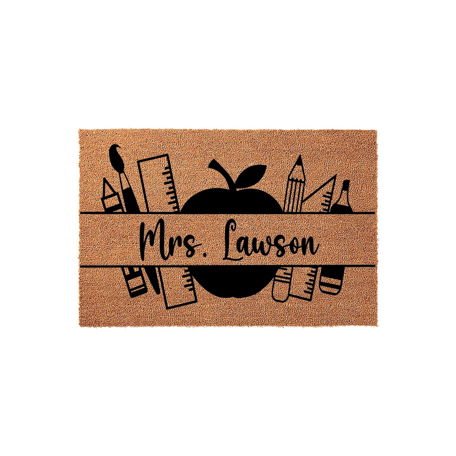 Personalized Teacher Coir Doormat featuring a black apple graphic and school supply icons like rulers and pencils, with a custom name space centered on a natural tan fiber background for a classroom or home entrance decor.