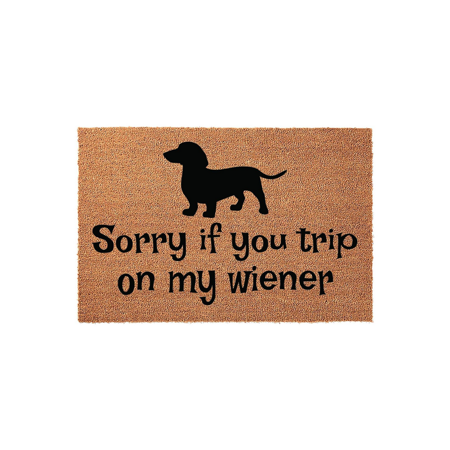 Dachshund Dog Welcome Doormat featuring a black silhouette of a wiener dog and the humorous text Sorry if you trip on my wiener printed on a natural tan coir fiber mat, creating a fun and welcoming entrance for any dog lover's