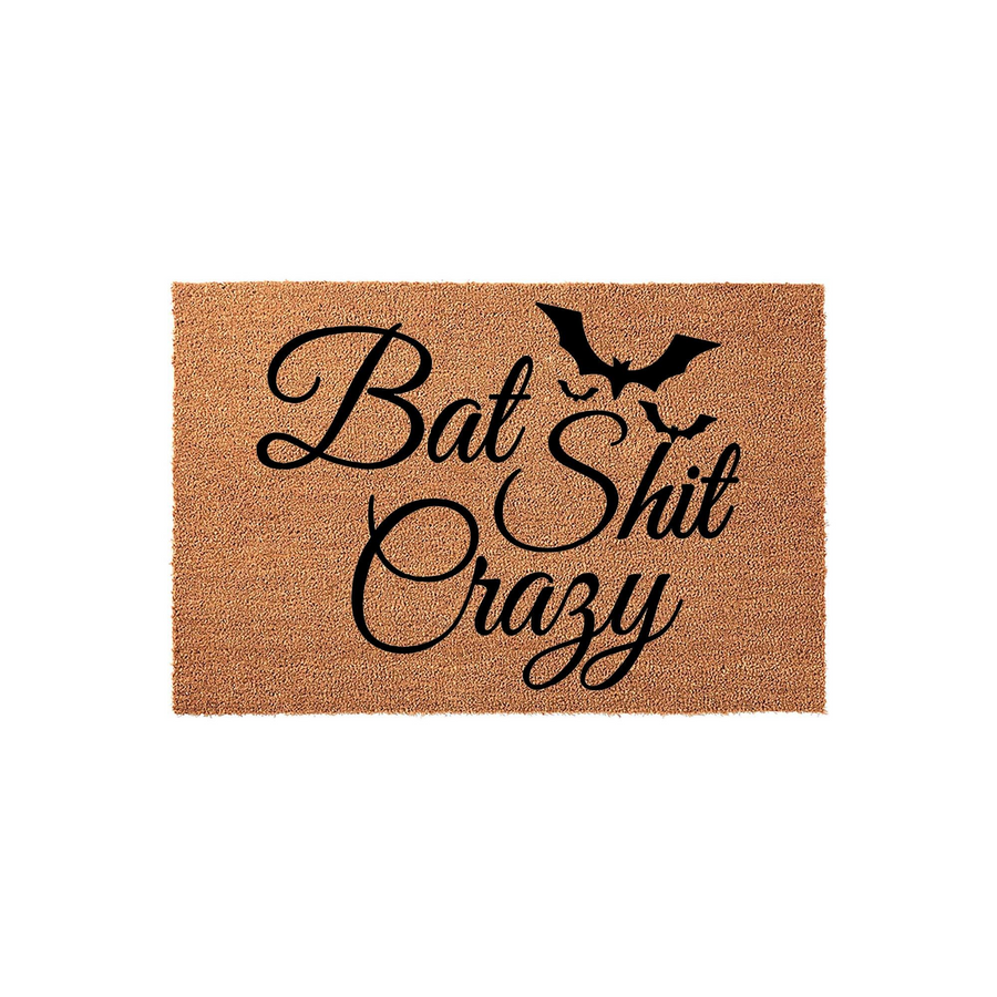 Funny Bat Shit Crazy coir doormat featuring a black silhouette of a flying bat above bold, cursive typography on a natural brown textured fiber background, perfect for a humorous Halloween or gothic home entryway decor statement.