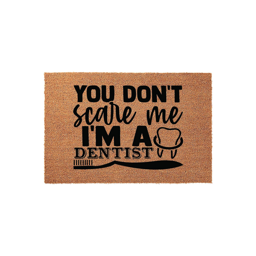 Dentist coir doormat featuring the humorous text You Don't Scare Me I'm A Dentist with a tooth icon and a toothbrush graphic, presented on a natural brown coconut fiber mat against a clean white studio background for a