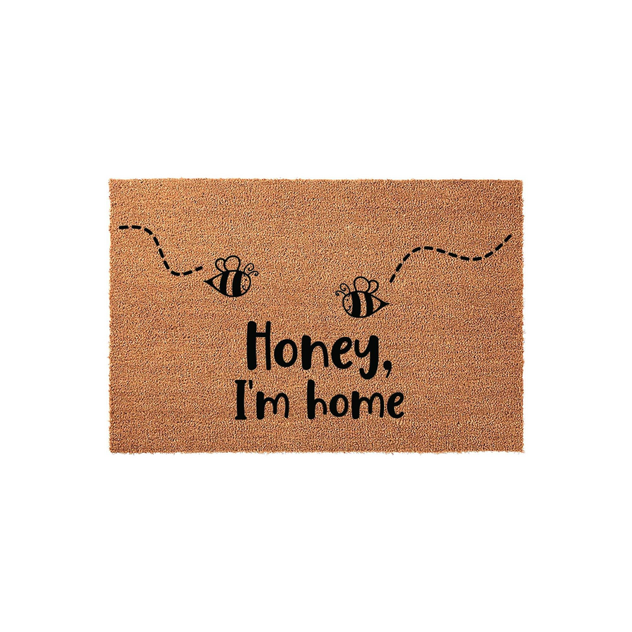 Honey I'm Home bee themed coir doormat featuring two cute illustrated bumblebees with dashed flight paths printed in black ink on a natural brown textured coir fiber background for a fun and welcoming front porch entryway decor.