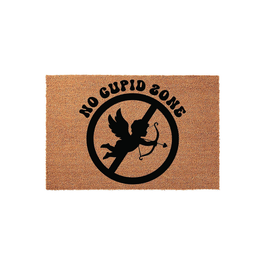 No Cupid Zone coir doormat featuring a black silhouette of a cherub inside a circular prohibition sign, printed on a natural brown textured coconut fiber mat for a humorous Valentine's Day or anti-romance home entryway decoration.