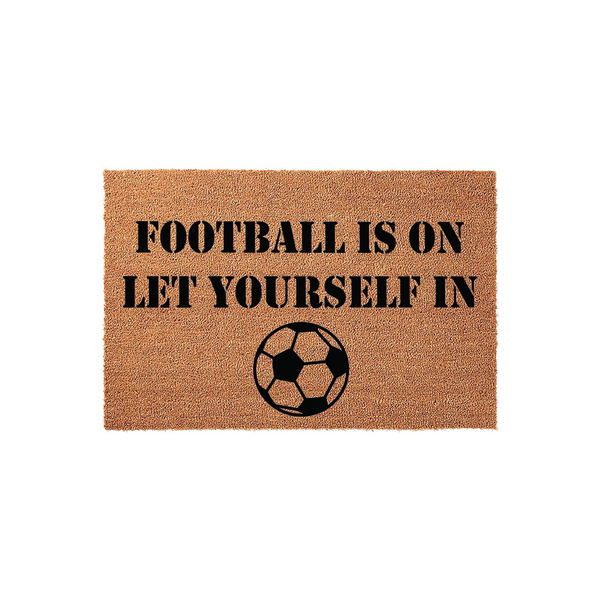 Football Is On Let Yourself In coir doormat featuring a natural brown fiber texture and bold black stencil text, accented with a classic soccer ball graphic centered at the bottom for a fun sports-themed entryway decor piece.