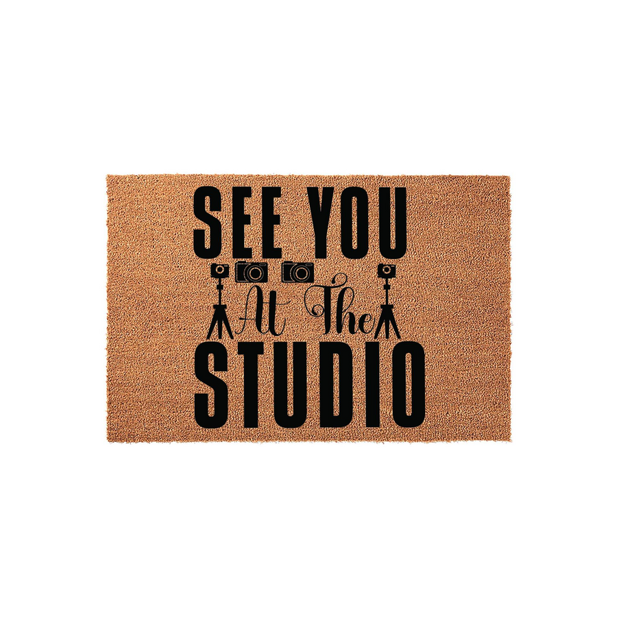 Photography Studio Coir Doormat featuring the text See You At The Studio in bold black lettering, accented by small camera and tripod icons on a natural brown textured coir fiber background for a professional photography business