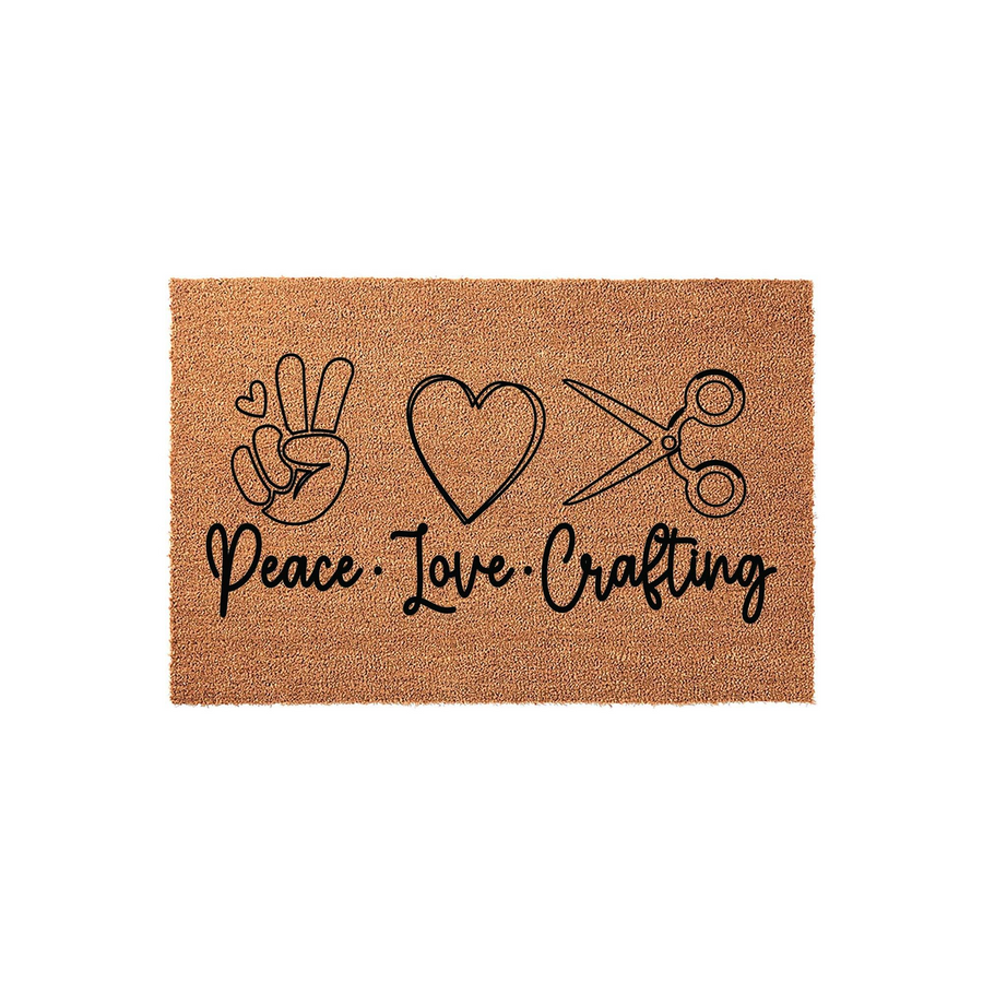 Peace Love Crafting coir doormat featuring a black printed design of a peace sign hand, a heart, and a pair of scissors on a natural tan fiber background, perfect for a craft room entrance or a creative home entryway decor.