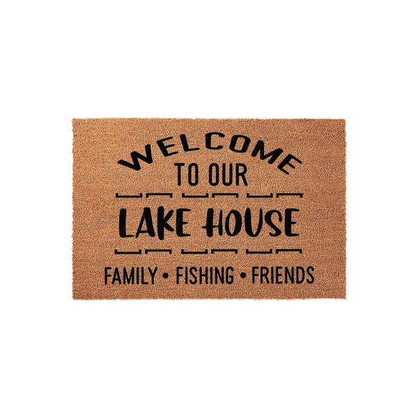 Lake House Welcome Doormat featuring a natural coir texture with bold black text that reads Welcome To Our Lake House, followed by the words Family, Fishing, and Friends, set against a clean white studio background for a rustic