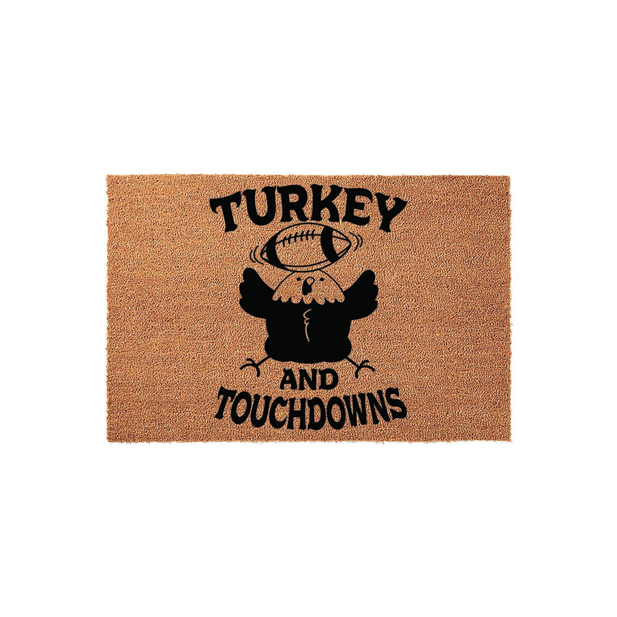 Turkey and Touchdowns Thanksgiving doormat featuring a cute black turkey illustration balancing a football on its head, printed in bold black ink on a natural tan coir fiber mat for a festive fall entryway decor style.