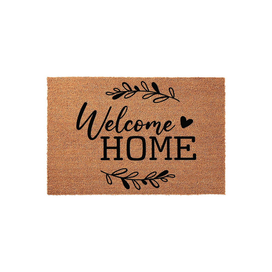 Welcome Home coir doormat featuring a natural tan fiber texture with black printed text and decorative leafy branch accents, creating a warm and inviting entryway aesthetic for your front porch or house entrance on a plain white