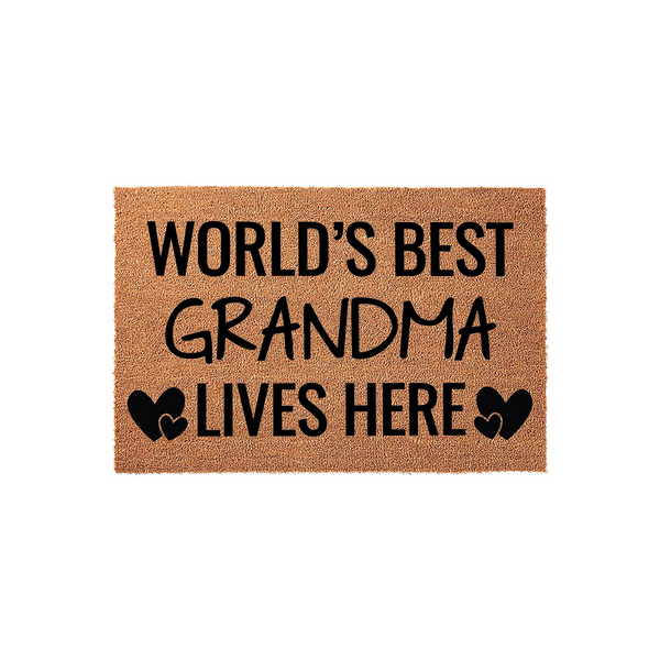 World's Best Grandma Lives Here coir doormat featuring bold black text and decorative heart icons on a natural brown fiber background, creating a welcoming entryway accent for a grandmother's home on a clean white studio backdrop.