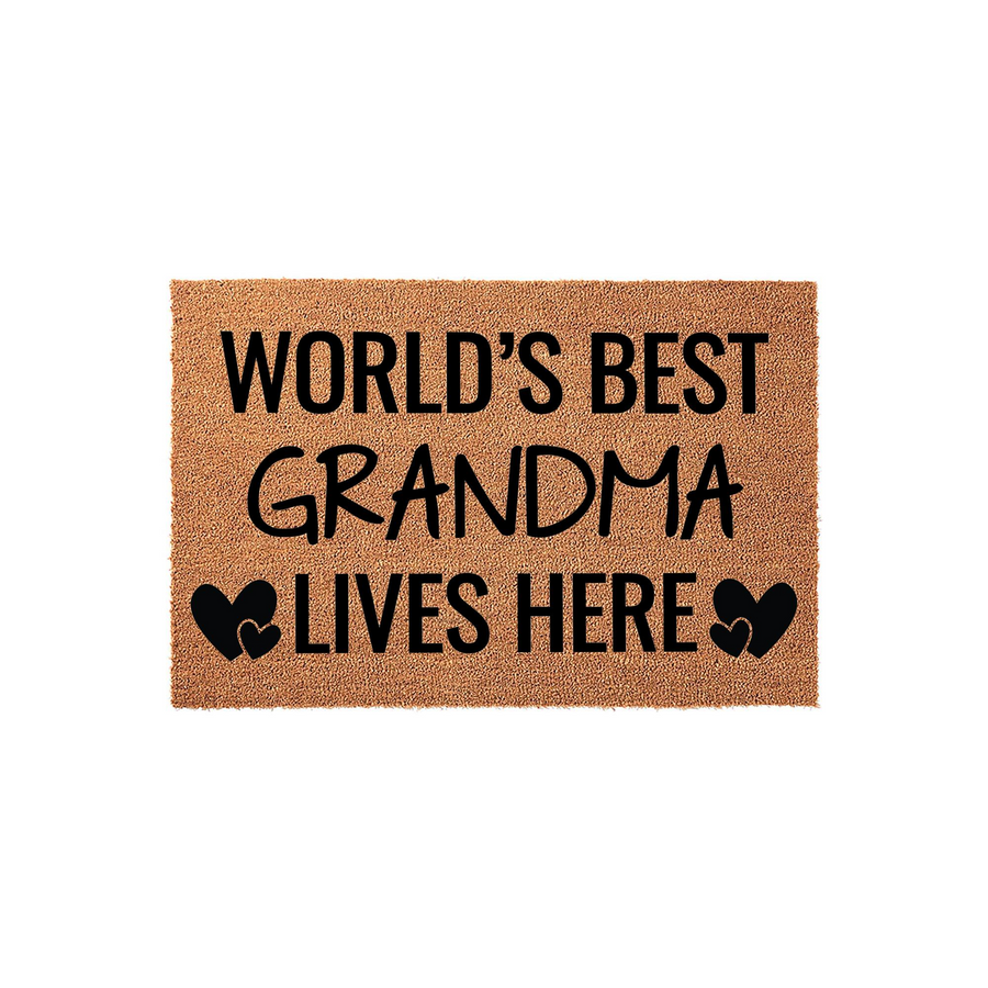 World's Best Grandma Lives Here coir doormat featuring bold black text and decorative heart icons on a natural brown fiber background, creating a welcoming entryway accent for a grandmother's home on a clean white studio backdrop.