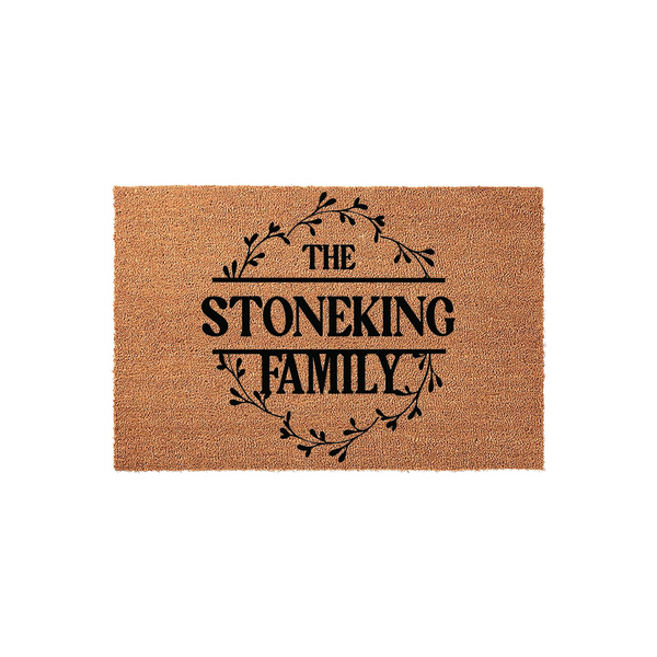 Personalized family name coir doormat featuring a rustic black leaf wreath design centered on a natural tan coconut fiber mat, providing a welcoming entrance decor piece for any home with custom last name text printed in bold