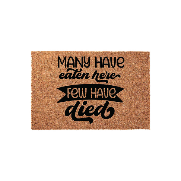 Funny Kitchen Doormat with the text Many Have Eaten Here Few Have Died printed in bold black lettering on a natural tan coir fiber mat, creating a humorous and welcoming accent for your home entryway or kitchen floor decor.