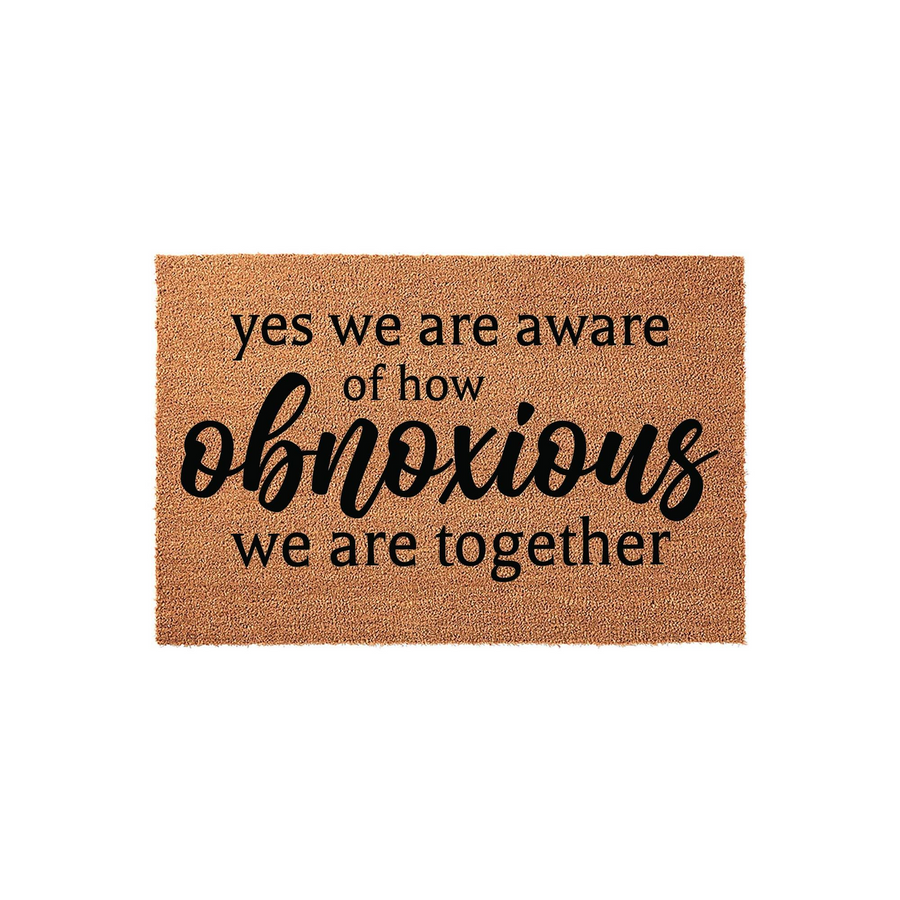 Funny doormat with the text yes we are aware of how obnoxious we are together printed in black script and serif fonts on a natural brown coir fiber background, creating a humorous welcome mat for a front porch or entryway home