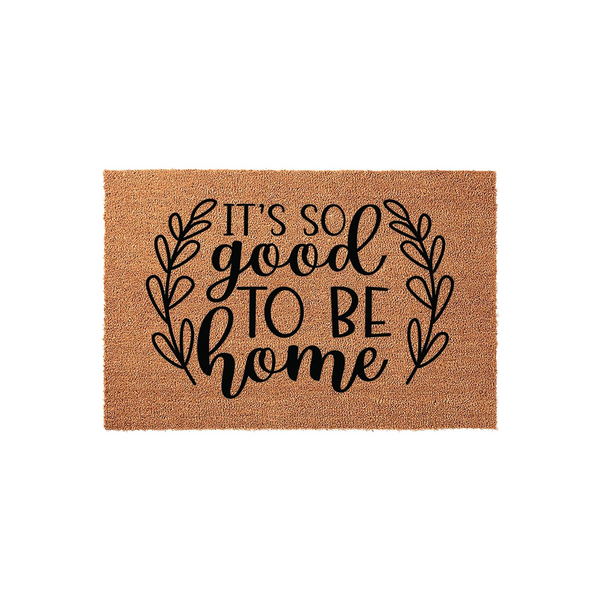 It's So Good To Be Home coir doormat featuring a natural brown fiber texture and black printed text surrounded by a decorative leaf wreath design, creating a welcoming entrance piece for your front porch or entryway floor decor.