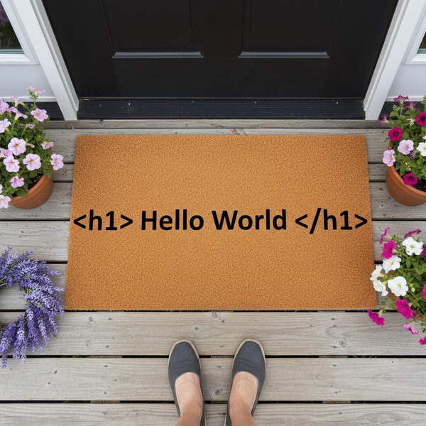 Hello World coir doormat featuring black text on a natural fiber mat, placed on a wooden porch with potted flowers and a person wearing gray shoes standing in front of the entrance to a home for a welcoming and geeky decor style.