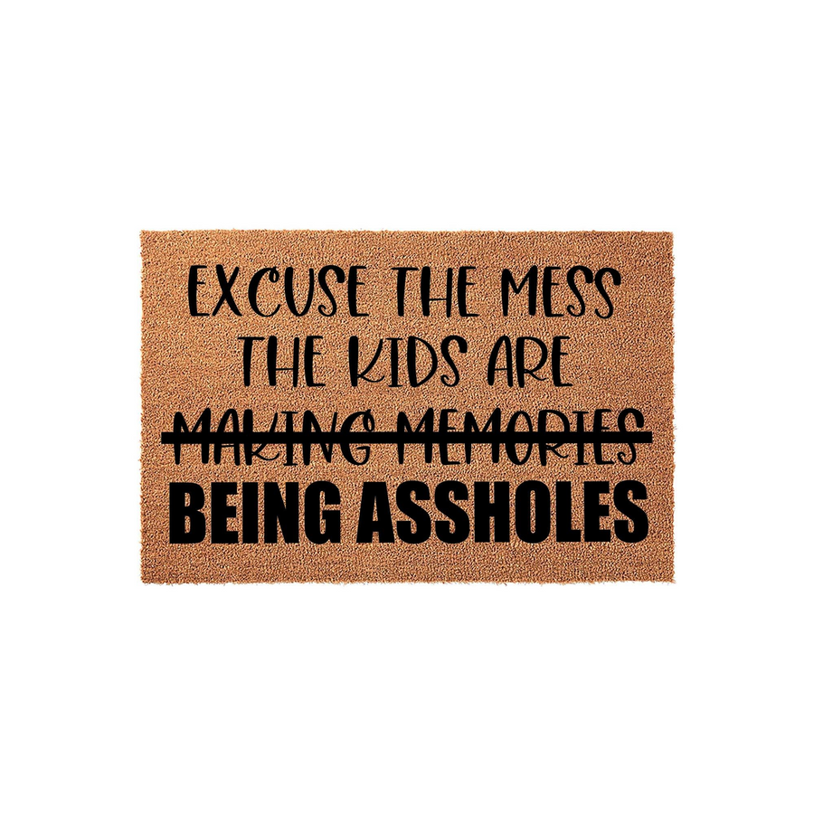 Funny Excuse The Mess Doormat featuring a natural coir texture with bold black text that reads Excuse the mess, the kids are making memories, being assholes, perfect for a humorous entryway decor statement in any family home.