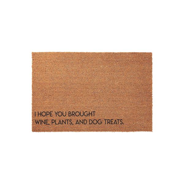 Funny coir doormat featuring the text I Hope You Brought Wine, Plants, and Dog Treats printed in black ink on a natural brown fiber background, making it a humorous and welcoming entrance mat for any home with pets and plant