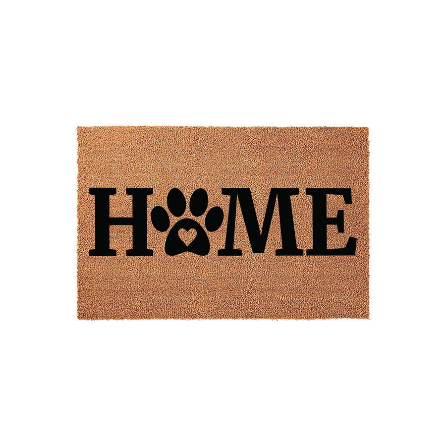 Home paw print coir doormat featuring a natural tan fiber texture and bold black lettering where the letter O is replaced by a cute dog paw print with a small heart cutout in the center, set against a clean white studio