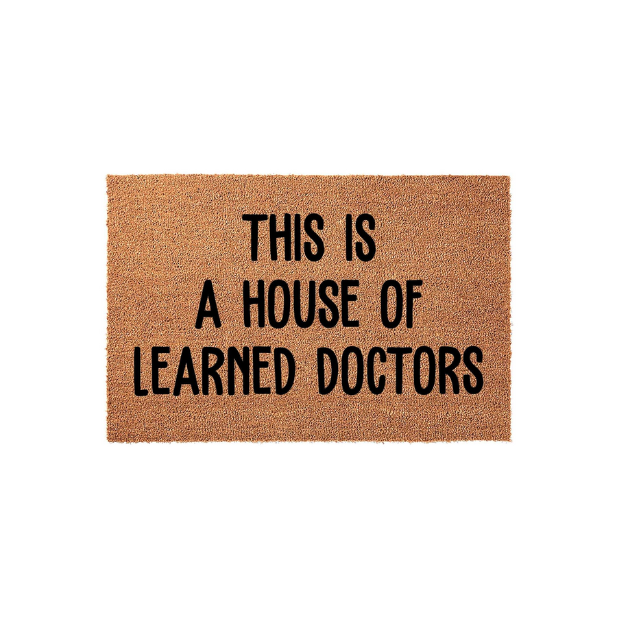 This is a House of Learned Doctors doormat featuring bold black lettering printed on a natural tan coir fiber mat, providing a humorous and professional welcome for the front porch of any medical professional or doctor's home.